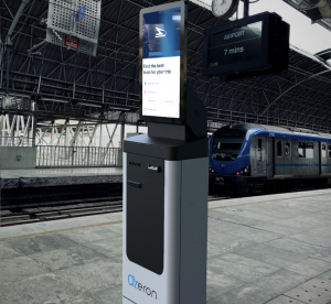 Customers use a kiosk near the parked train on a railway station platform for various purposes.