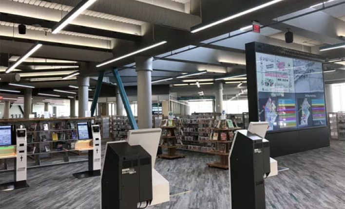 A large screen broadcasts information, and a lot of books arranged on the shelves in the library.